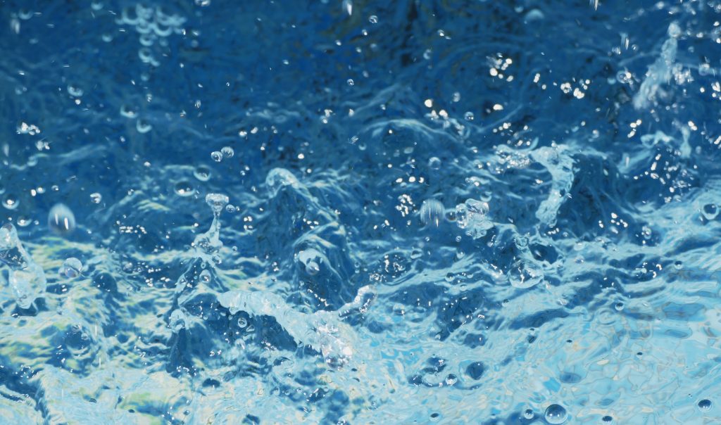 Przejrzysta, błękitna woda z bąbelkami na letnim tle